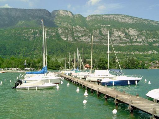 Jachthaven bij camping Jachthaven met zeilboten en een groene berg op de achtergrond.