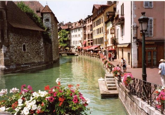 Oud Annecy Historisch stadsbeeld van Annecy met bloemen en een groene rivier langs kleurrijke gebouwen.