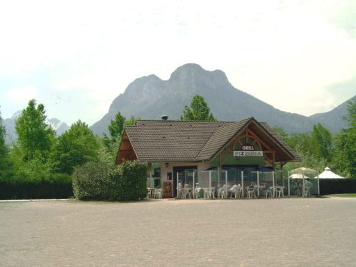 Restaurant Restaurant met terras, omgeven door bomen en op de achtergrond een berglandschap.